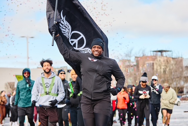 Jackie Hoffman leading runners with the Peace Runners flag